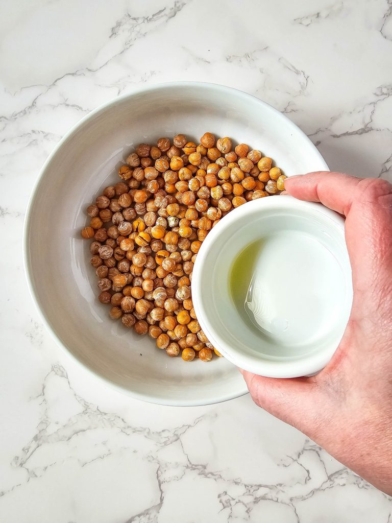 pouring oil over roasted chickpeas