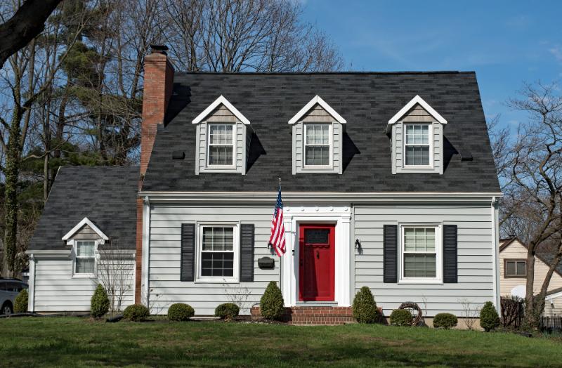 cape cod style house with gray siding and bright red door