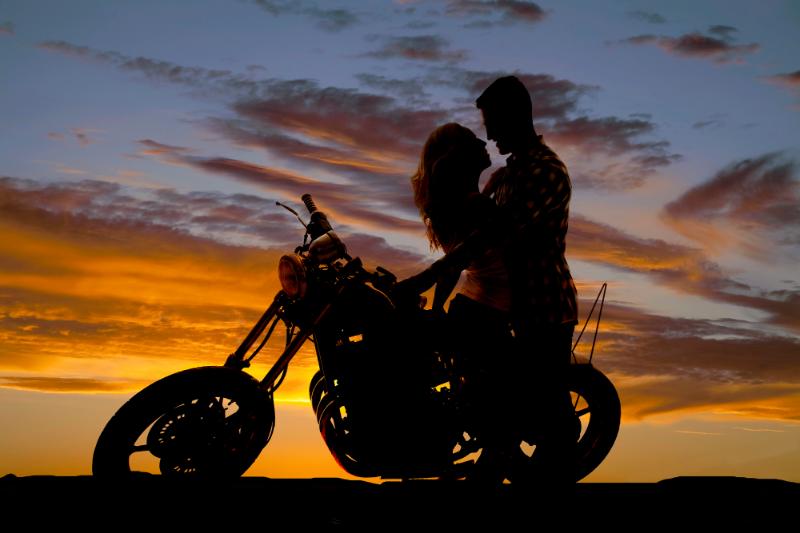 couple with motorcycle in silhouette at sunset
