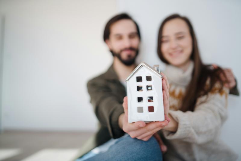 blurred couple holding a model of a home in their hands (model is in focus)