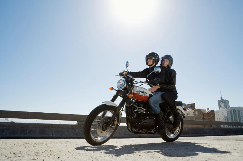 couple riding a motorcycle across a bridge