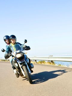 couple cruising down the road on a motorcycle on a sunny, clear day