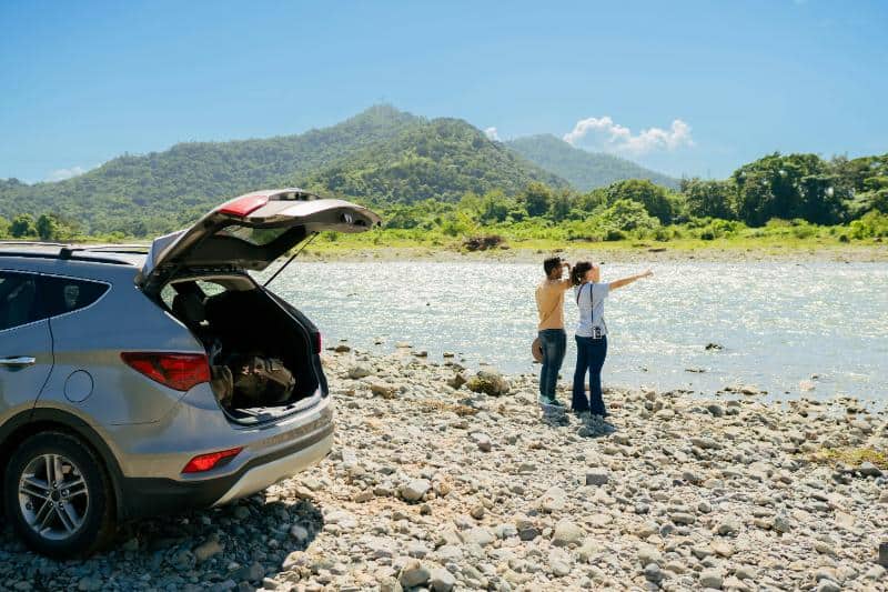 couple overlooking a stream, trunk of SUV open
