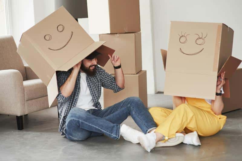 man and woman with decorated moving boxes on their heads