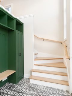 entryway at stairs with vibrant green storage cabinets with bench and cubbies
