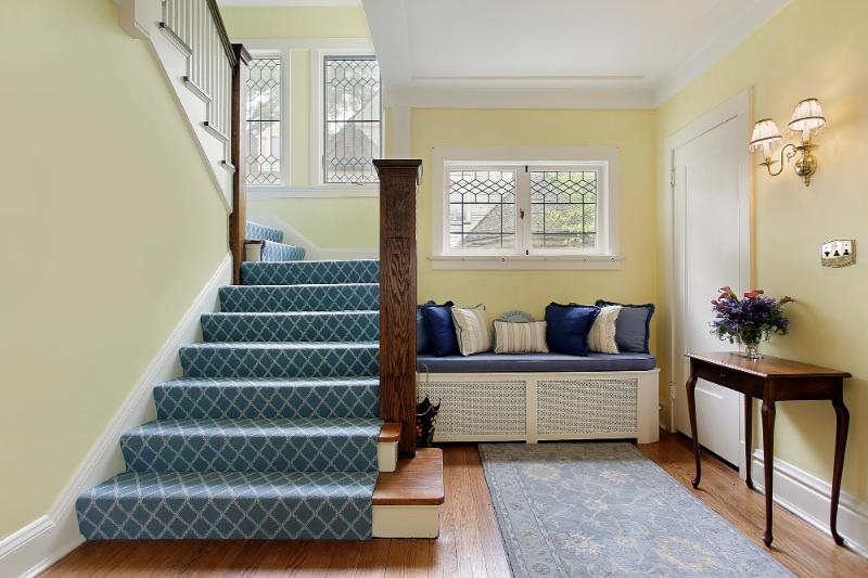 entryway with yellow walls, a staircase, a console table, and a bench with throw pillows