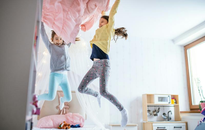 girls jumping on bed and smiling