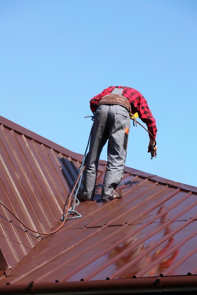man painting a metal roof