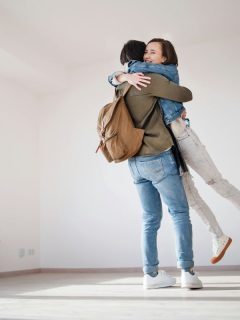 man lifting woman in an embrace in new home