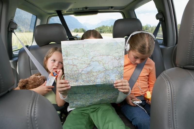 kids in car eating snacks and looking at a map