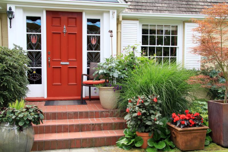 home with colorful front door and landscaping in various pots around the porch