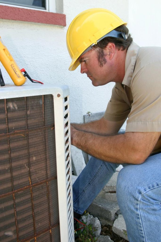 repairman working on old AC unit