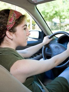 teen girl with brown hair with both hands on wheel
