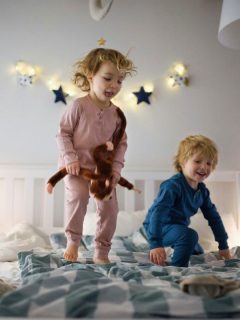 toddlers jumping on the bed, starry lights in background