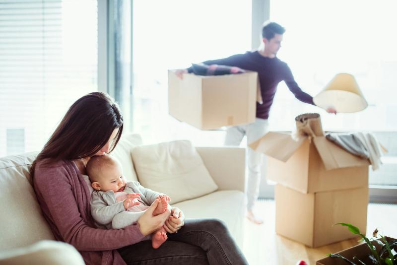 wife holding baby while husband unpacks