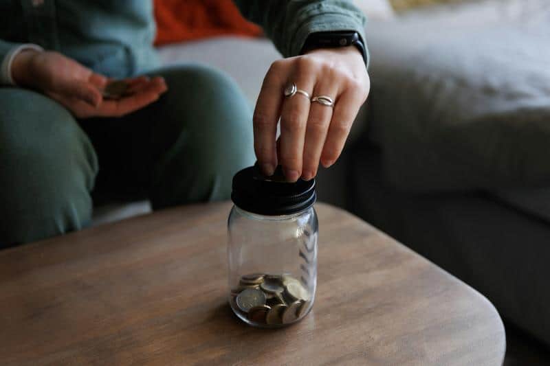 woman adding change to a jar of coins