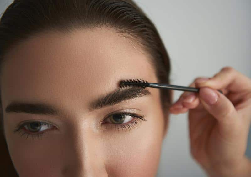 woman with natural brows getting them brushed