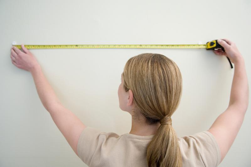 blonde woman measuring a wall