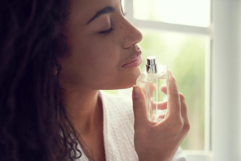 woman smelling an empty perfume bottle