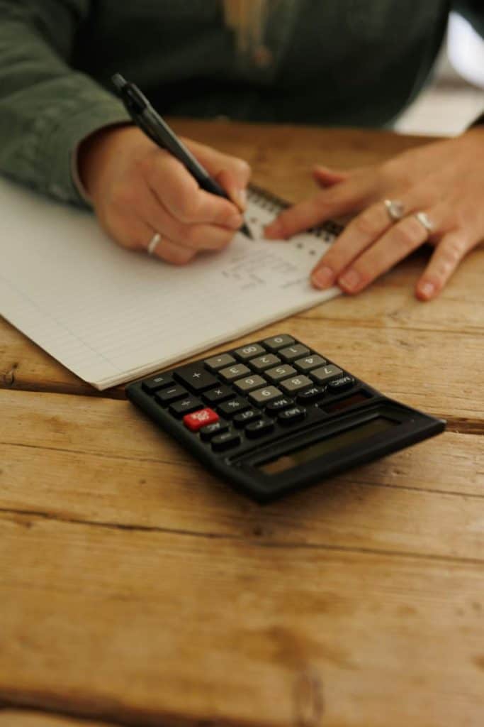 woman creating a budget using a notebook and pen and using a calculator