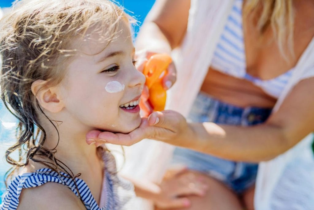 applying sunscreen to little girl's face