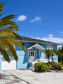 blue beach house with palm trees on a sunny day