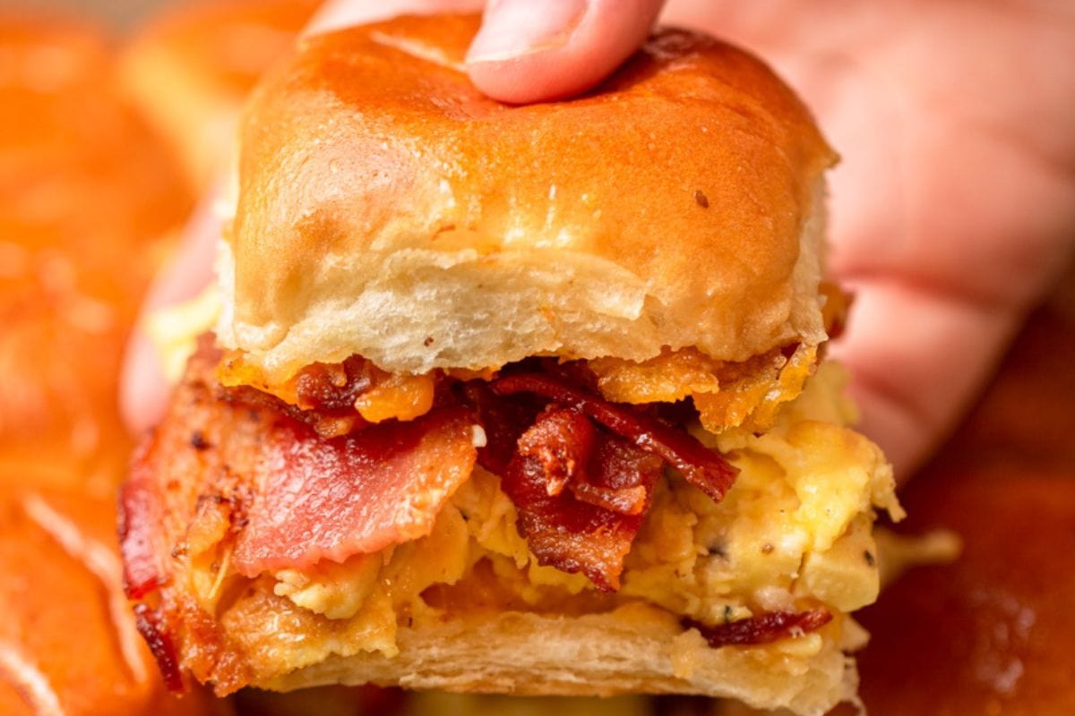 a hand holding a breakfast slider