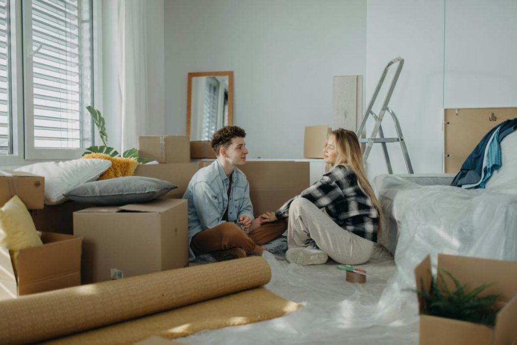 couple sitting on the floor of a new apartment surrounded by boxes
