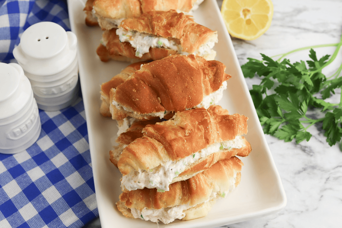 crab salad sandwiches on white plate with blue checkered napkin to the left