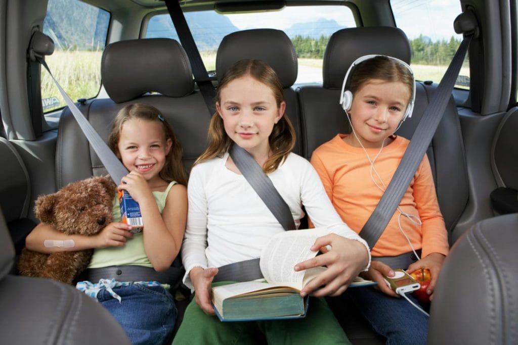 kids in backseat with toys, books, headphones