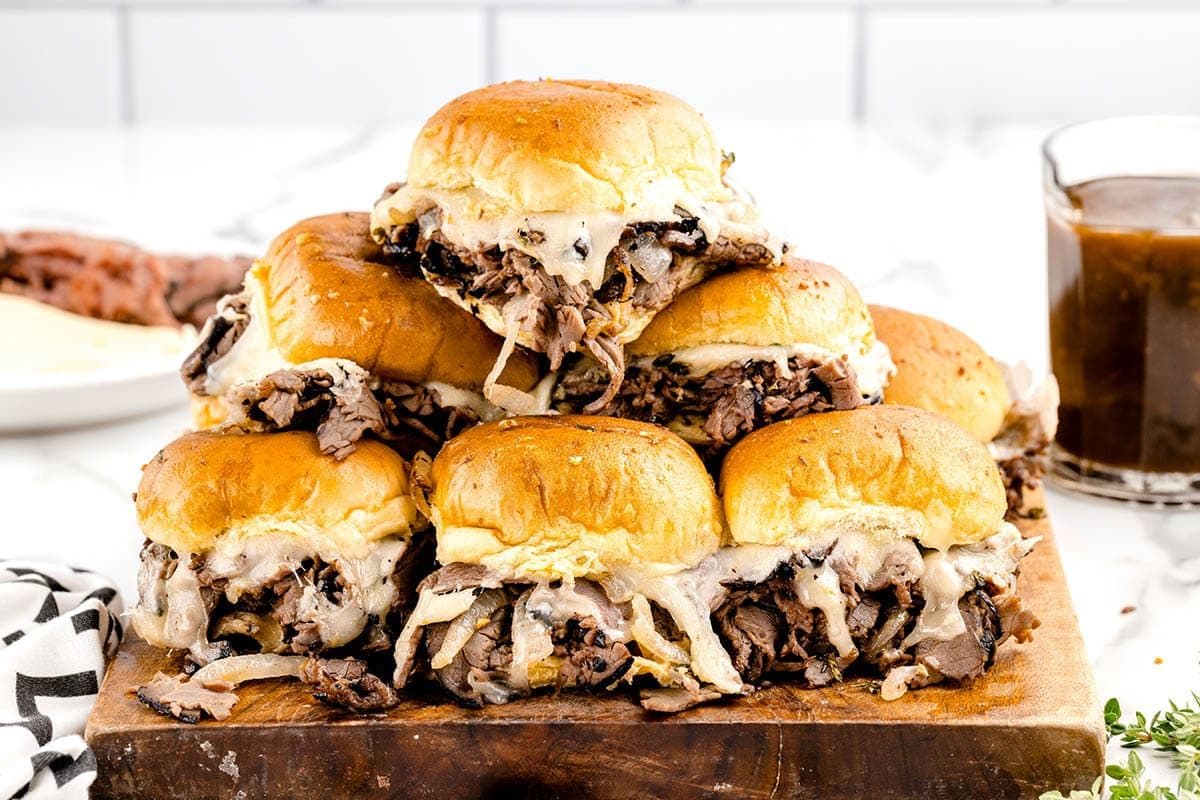 stacked french dip sliders on wooden cutting board