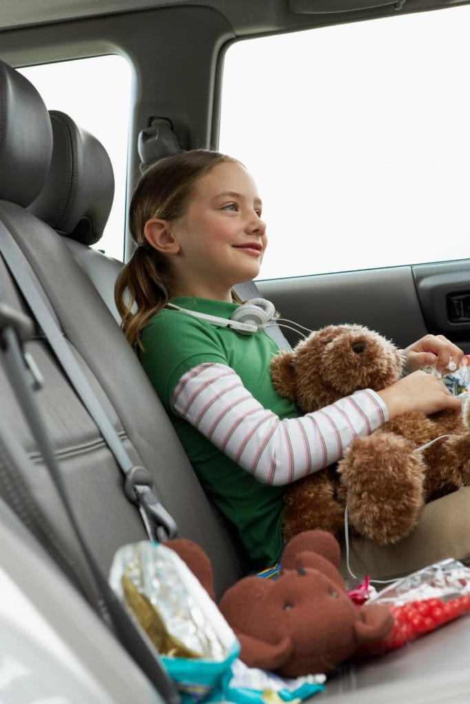 girl holding teddy bear in car