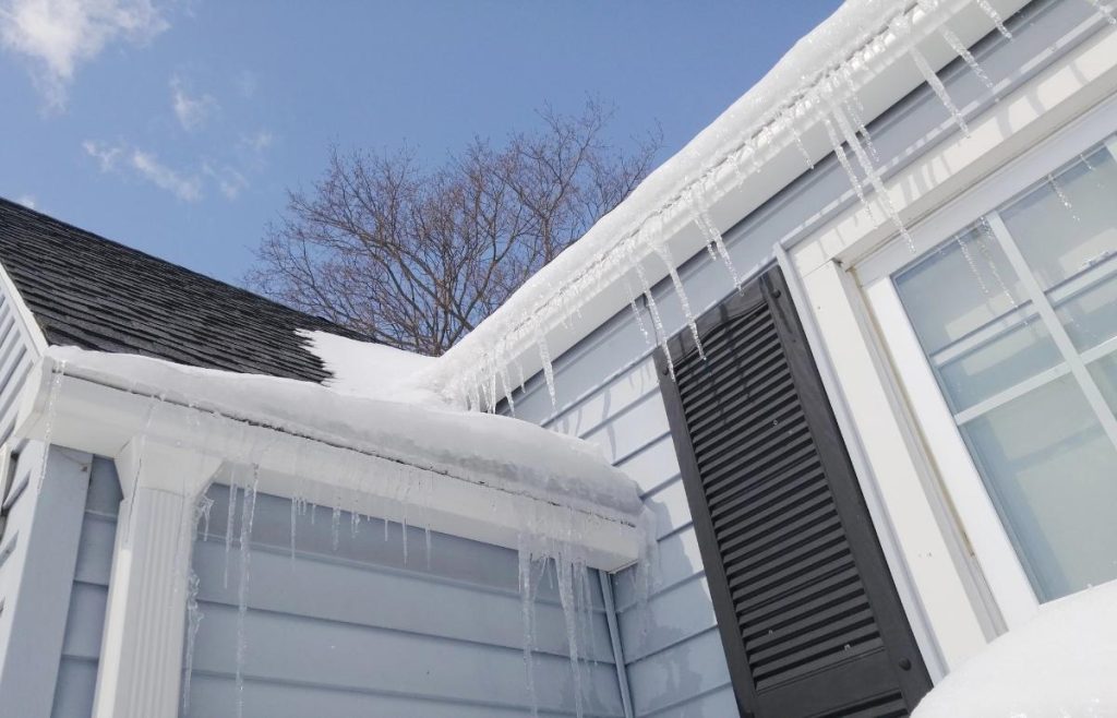 icicles hanging off the roof of a gray house