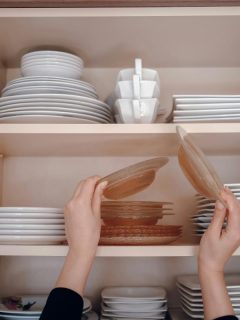 woman putting plates in kitchen cabinet