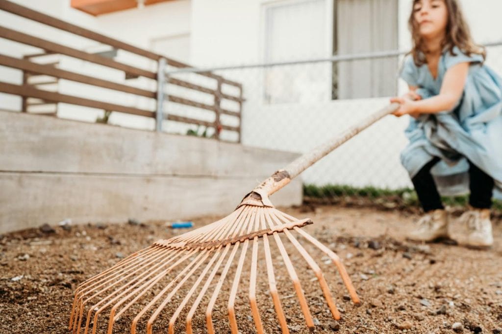 girl using a rake to clear an area