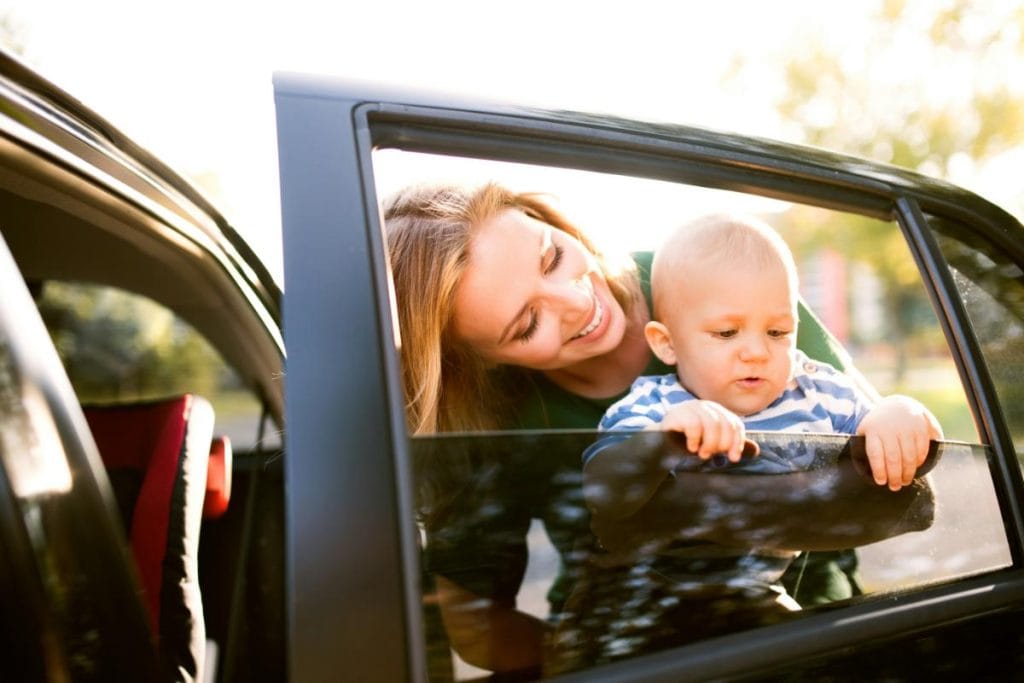 view of mom and baby through car window, mom putting baby in car