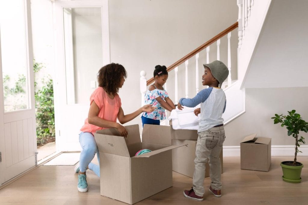 mom, son, and daughter unpacking boxes in new home
