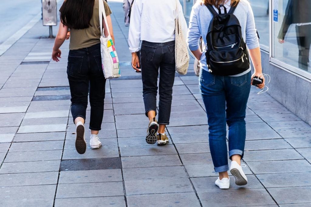 group of people wearing jeans walking down street