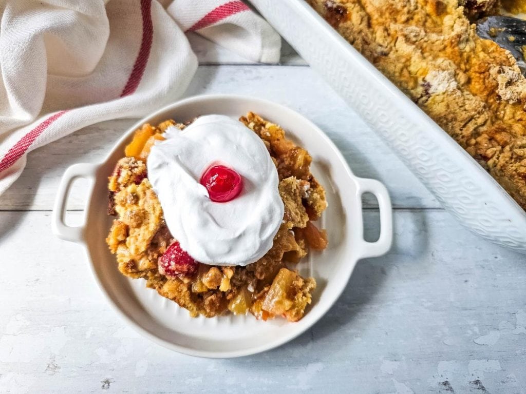 upside down pineapple dump cake with whipped cream and a cherry