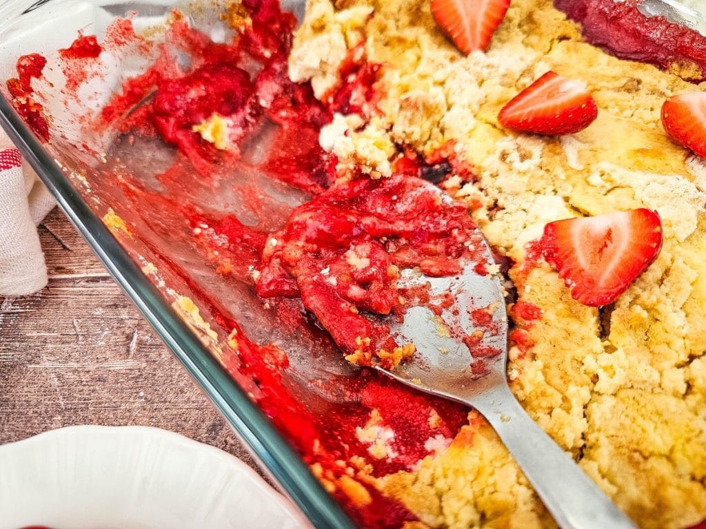 baking pan with strawberry dump cake and some scooped out