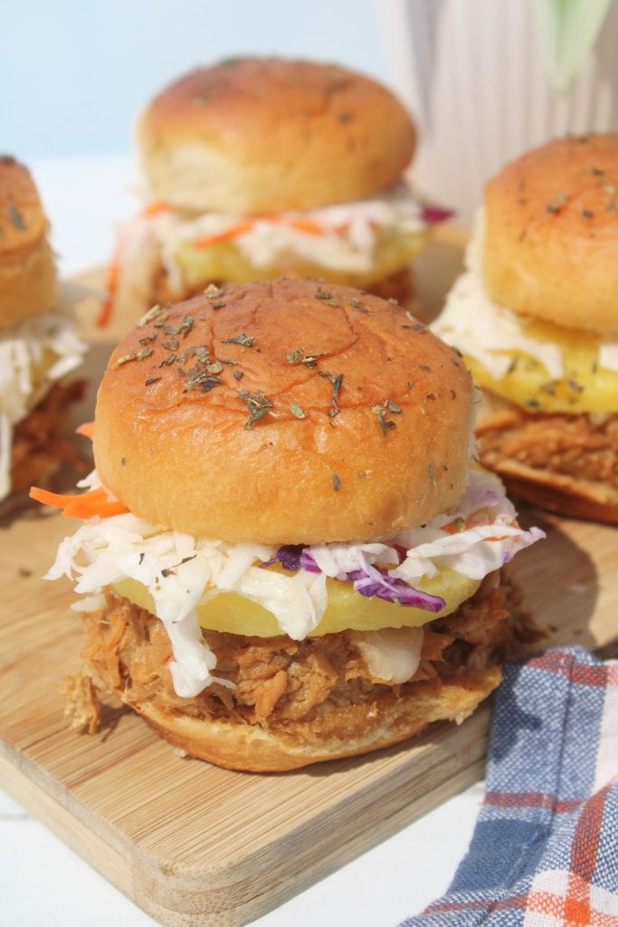 delicious chicken teriyaki sliders topped with pineapple slices and coleslaw