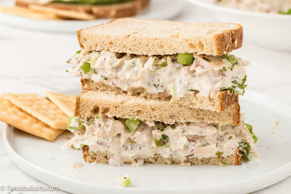 tuna salad sandwich cut in half and stacked on white plate