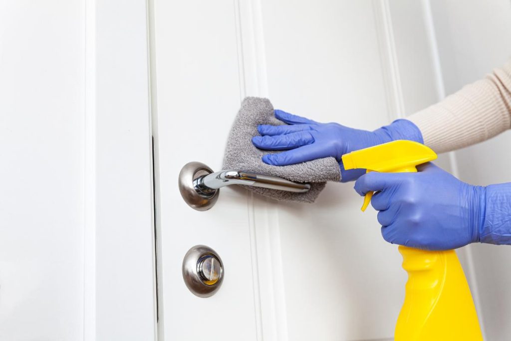 using a soft cloth and cleaner to wipe down a door
