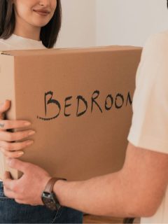 woman handing box labeled bedroom to man