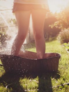 woman cooling off in garden using water hose