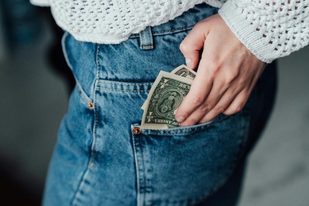 woman putting dollar bills in pocket