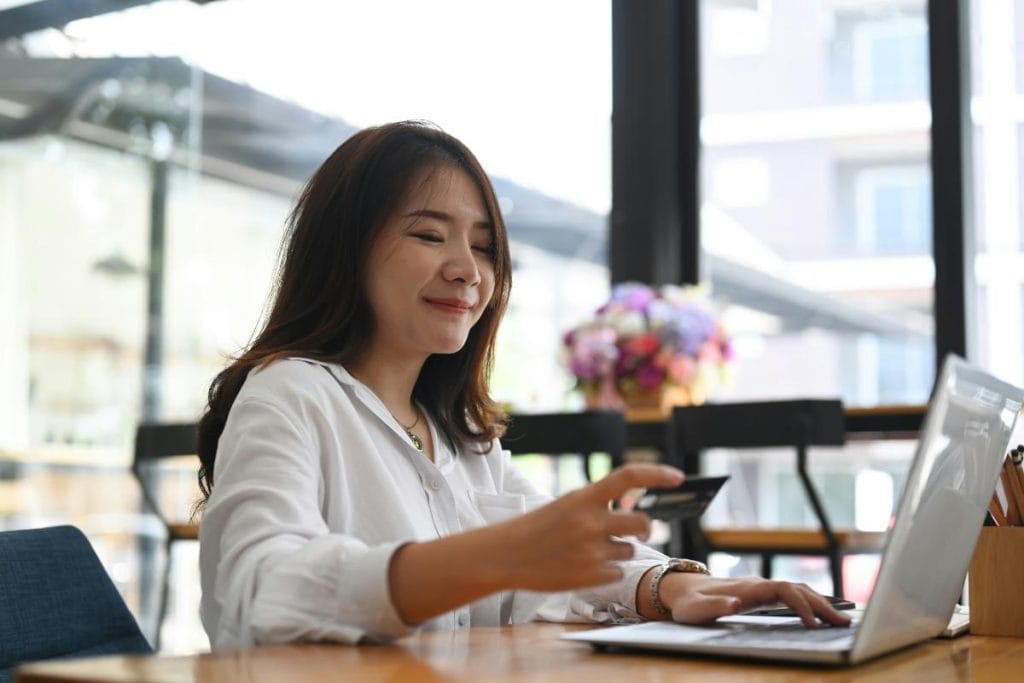 woman sitting at table with laptop and credit card