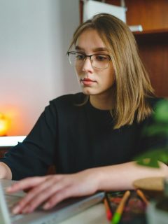 woman using laptop while wearing glasses