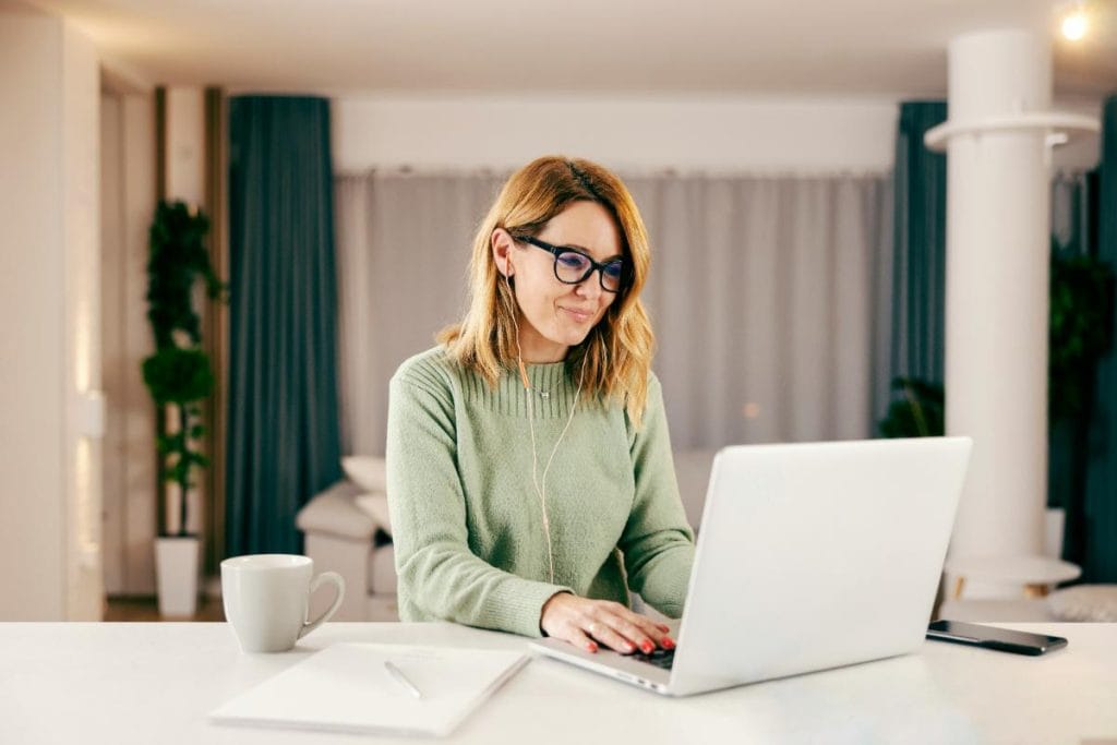 woman using earbuds and laptop