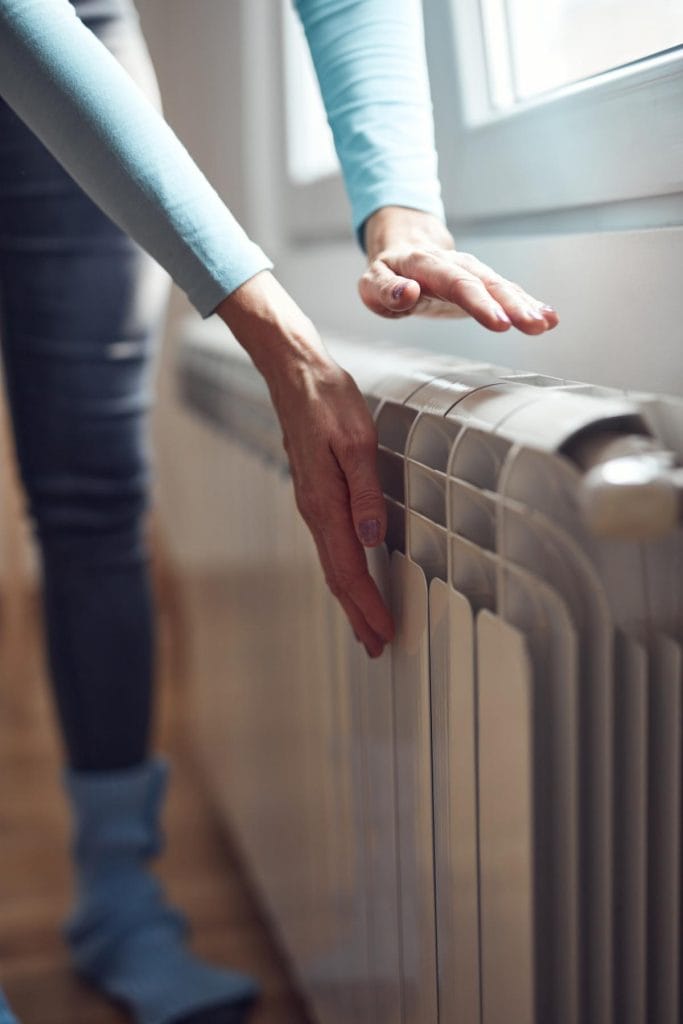 woman with hands near radiator